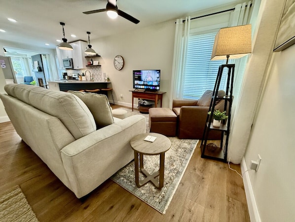 Cozy living area with smart TV, comfy seating, and open kitchen concept.