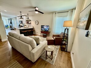 Cozy living area with smart TV, comfy seating, and open kitchen concept.
