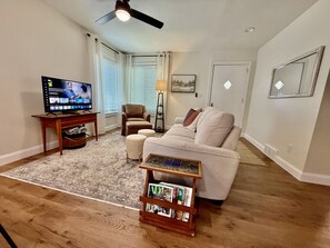 Cozy living area with smart TV, comfy seating, and open kitchen concept.