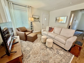 Cozy living area with smart TV, comfy seating, and open kitchen concept.