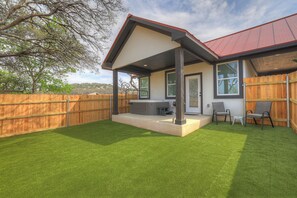 The backyard patio invites you to relax with a soak in the hot tub, unwind in the comfortable seating area, or fire up the charcoal grill for an evening barbecue.