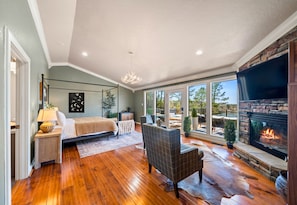 Wake up to stunning lake views from this luxurious bedroom, featuring a cozy fireplace and comfortable seating for quiet mornings.