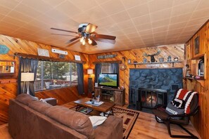 Step into our inviting living space, where the rustic charm of wooden decor meets the warmth of a crackling fireplace.
