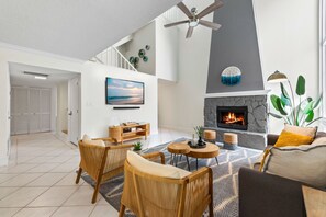 Cozy up at Seabreeze Villa 🔥 This inviting living room features a warm fireplace and coastal-inspired decor—perfect for relaxing after a day at the beach. Your seaside escape is just a booking away! 🌴✨