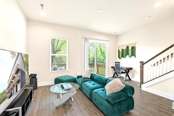 A plush couch and a big-screen smart TV plus a balcony access.