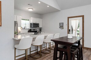 Dining area with high top table for 4 and 4 bar stools at kitchen island