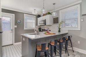 Unit 1: Bright and modern, this kitchen shines with a sleek marble countertop, stylish lighting, and everything you need for a perfect meal or casual gathering.