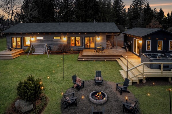 Idyllic private backyard with hot tub, fire pit, and several seating areas.