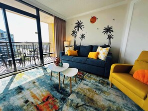 Sunny vibes meet modern comfort in this stylish living area with vibrant seating, beachy wall art, and direct access to your private balcony with ocean views just steps away.