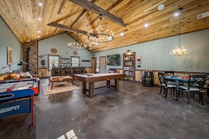 Spacious game room with vaulted ceilings, a pool table, air hockey, poker table, cozy seating, and a built-in bar. Perfect for game nights and relaxing after a day of mountain adventures.