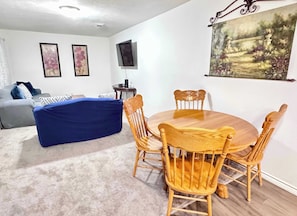 The open concept shared living area flows from the kitchen, to dining area, and into the living room. There is additional seating for 4 at the dining tables and comfortable seating and large TV in the living area.