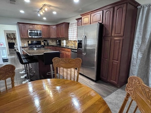 The open concept living area flows from the kitchen, to dining area, and into the living room. There is additional seating for 4 at the dining table. The fridge has a shelf assigned to each private room guest.