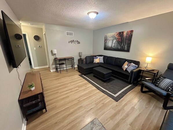 Spacious living room with work area, 60" Roku Smart TV, lounge chair.