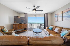 Spacious and inviting living area with plush seating and direct access to the balcony overlooking the ocean.