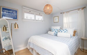 Charming bedroom with a queen bed, soft coastal hues, and a peaceful setting for restful nights.