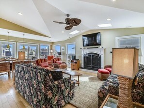 Cozy living room with comfortable seating, a ceiling fan, and an entertainment center.