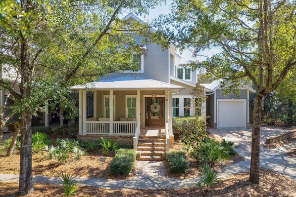 Charming house on a tree lined street with cozy front porch swing and seating.