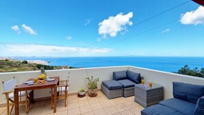 Spacious terrace at Desertas Vista Ninho in Gaula, Santa Cruz, featuring a cozy outdoor sofa with cushions and a stylish dining table—perfect for relaxing or enjoying meals with stunning ocean and Desertas Islands views. #sofa