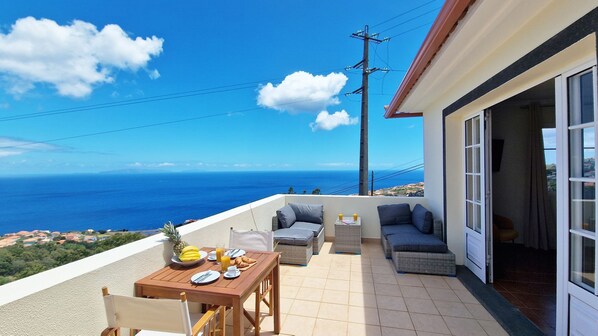 Spacious terrace with comfortable outdoor furniture, offering stunning ocean views and a breathtaking sight of the Desertas Islands. Desertas Vista Ninho in Gaula, Santa Cruz is your serene escape. #terrace #oceanview #desertsislands