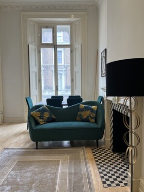 The magnificent living room with high (3.8m) ceilings, wooden floors and tall balcony windows