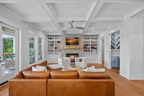 Large open concept living room with leather sectional, 2 chairs and large TV.