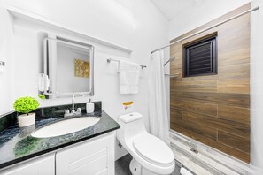 Modern bathroom with walk-in shower, soap, and body wash provided.