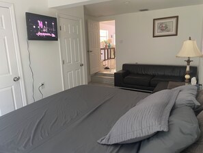 This bedroom includes a King bed with a beside table, Smart TV, and couch.