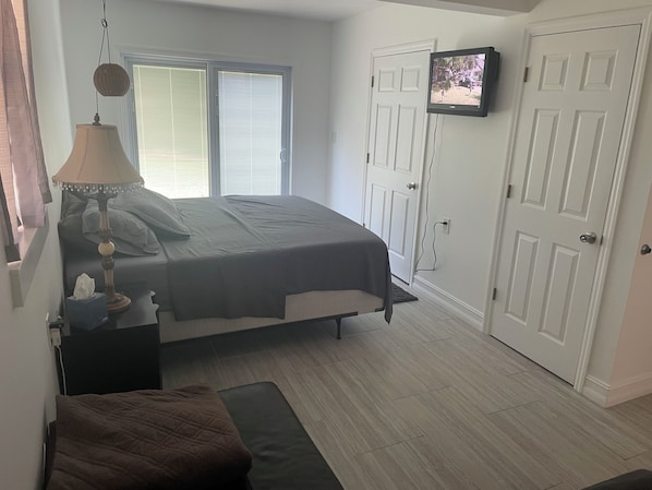 This bedroom includes a King bed with a beside table, Smart TV, and couch.