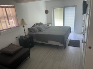 This bedroom includes a King bed with a beside table, Smart TV, and couch.