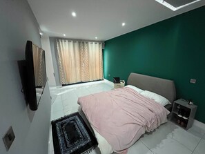 En-suite bedroom with double bed, wardrobe, dressing table & TV.