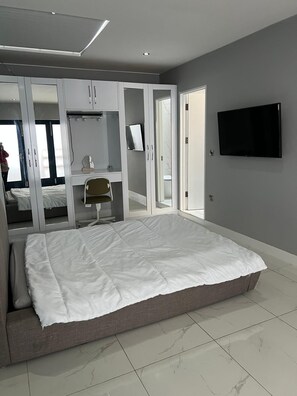 En-suite bedroom with double bed, wardrobe, dressing table & TV.