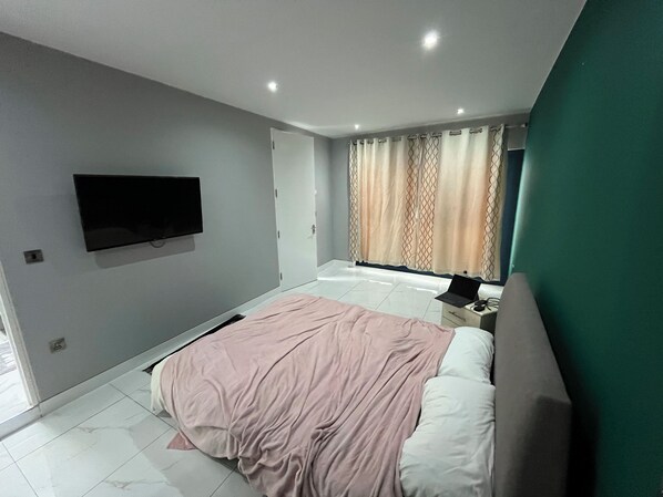 En-suite bedroom with double bed, wardrobe, dressing table & TV.