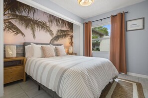This cozy bedroom offers a queen bed, a calming tropical mural, and a smart TV.