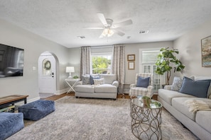 Large living Room with plush couches, recliner and game table with a 65" TV