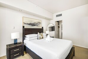 A calming atmosphere with modern art and warm accents. A bright and inviting bedroom, designed for comfort and relaxation with a touch of modern elegance. The focus is on the well-made bed, promising a restful night's sleep, while the room's clean lines and contemporary art create a calming atmosphere.