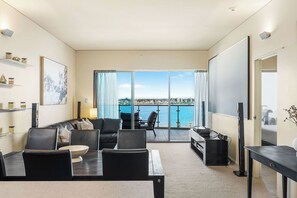Relax in a bright and spacious open-plan living area, seamlessly blending a dining space, living room, and balcony access, all with stunning waterfront views.