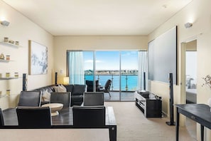 Relax in a bright and spacious open-plan living area, seamlessly blending a dining space, living room, and balcony access, all with stunning waterfront views.