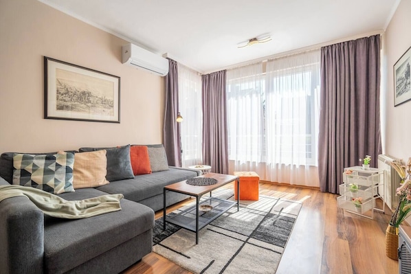You’ll relax in a spacious living room with a smart TV, blackout curtains, and a super comfy convertible sofa that turns into a double bed — perfect for movie nights or deep sleep after a long day out.