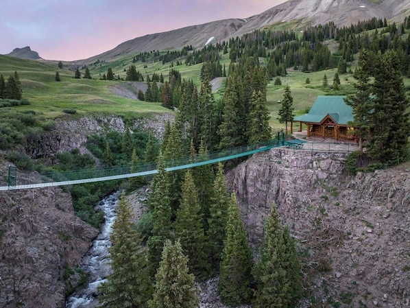 Aerial view of the suspension bridge and cabin. Wildhorse Peak is in background