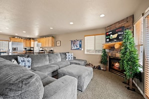 A modern electric stone fireplace creates a warm, inviting centerpiece, perfectly framed by a spacious sectional couch where everyone can unwind.