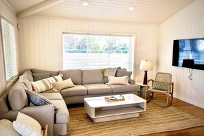 Kick back and relax in this bright and cozy living room, an oversized sectional offers plenty of space for movie nights or simply stretching out after a long day of exploring the coast.