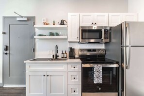 Fully equipped kitchen with refrigerator, microwave, stove, oven, dishwasher, toaster, teapot, and Keurig coffee machine.