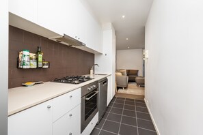 Galley style kitchen with stone bench tops, gas stove and stainless steel dishwasher