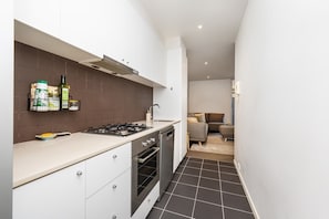 Galley style kitchen with stone bench tops, gas stove and stainless steel dishwasher