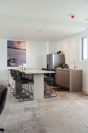 Where modern minimalism meets everyday comfort—sleek counters, cozy bar stools, and a space that’s made for coffee breaks, quick bites, and long chats.