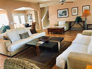 Spacious, open-concept living room with cozy designer sofas, modern decor, and natural light—perfect for relaxing or entertaining.