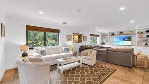 Spacious open floor plan featuring two inviting living room areas, smart TV, books, and games—perfect for relaxing or entertaining. Enjoy seamless access to the kitchen and a private balcony with outdoor dining for four.