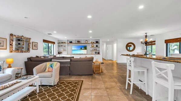 Spacious open floor plan featuring two inviting living room areas, smart TV, books, and games—perfect for relaxing or entertaining. Enjoy seamless access to the kitchen and a private balcony with outdoor dining for four.