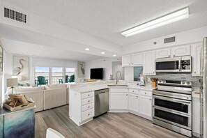 Bright, modern kitchen with stainless steel appliances and scenic balcony view.