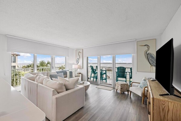 Bright living room overlooking the water, complete with comfy seating and deck access.